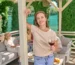 Woman enjoying wine in a custom garden structure design featuring comfortable seating and decorative elements.